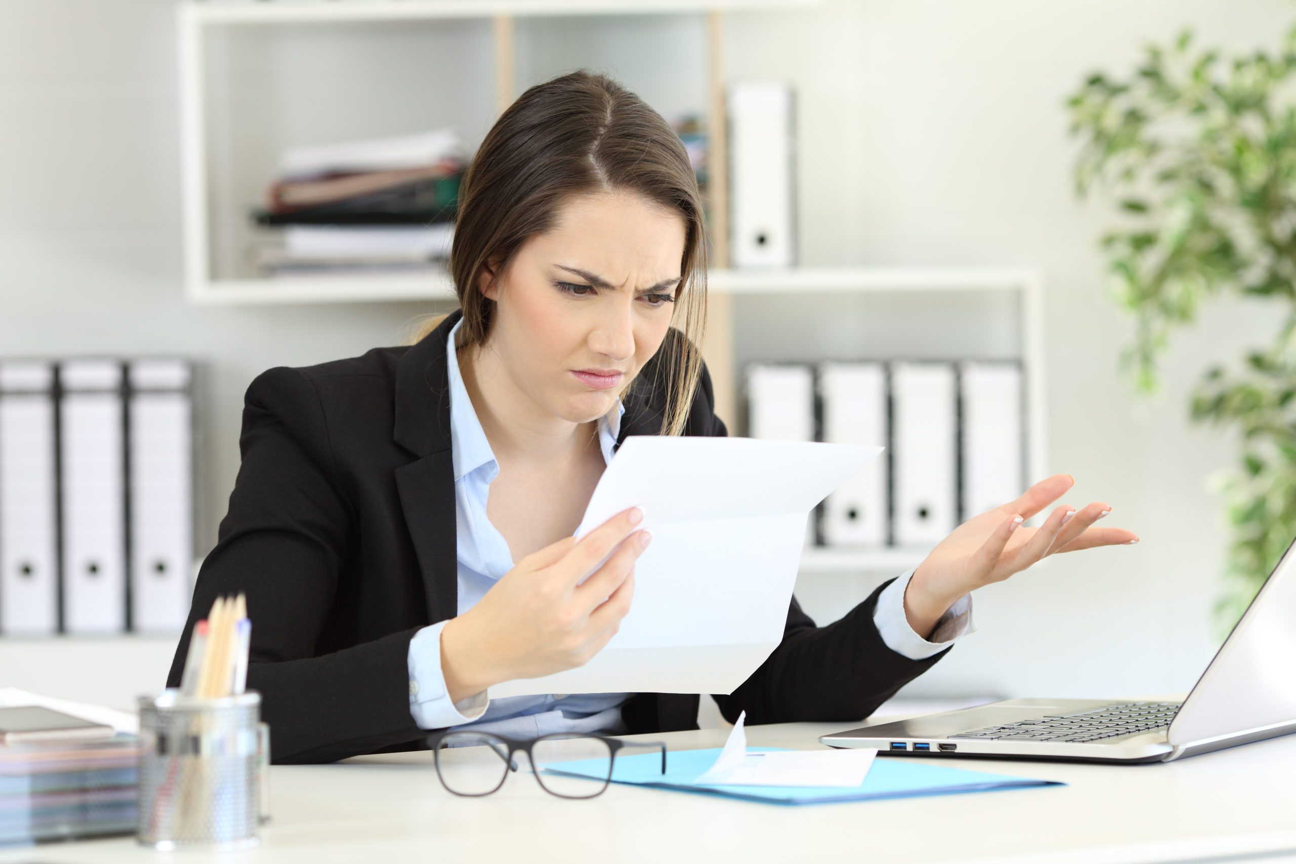 Business woman with document looking confused wondering if her insurer will pay out her claim