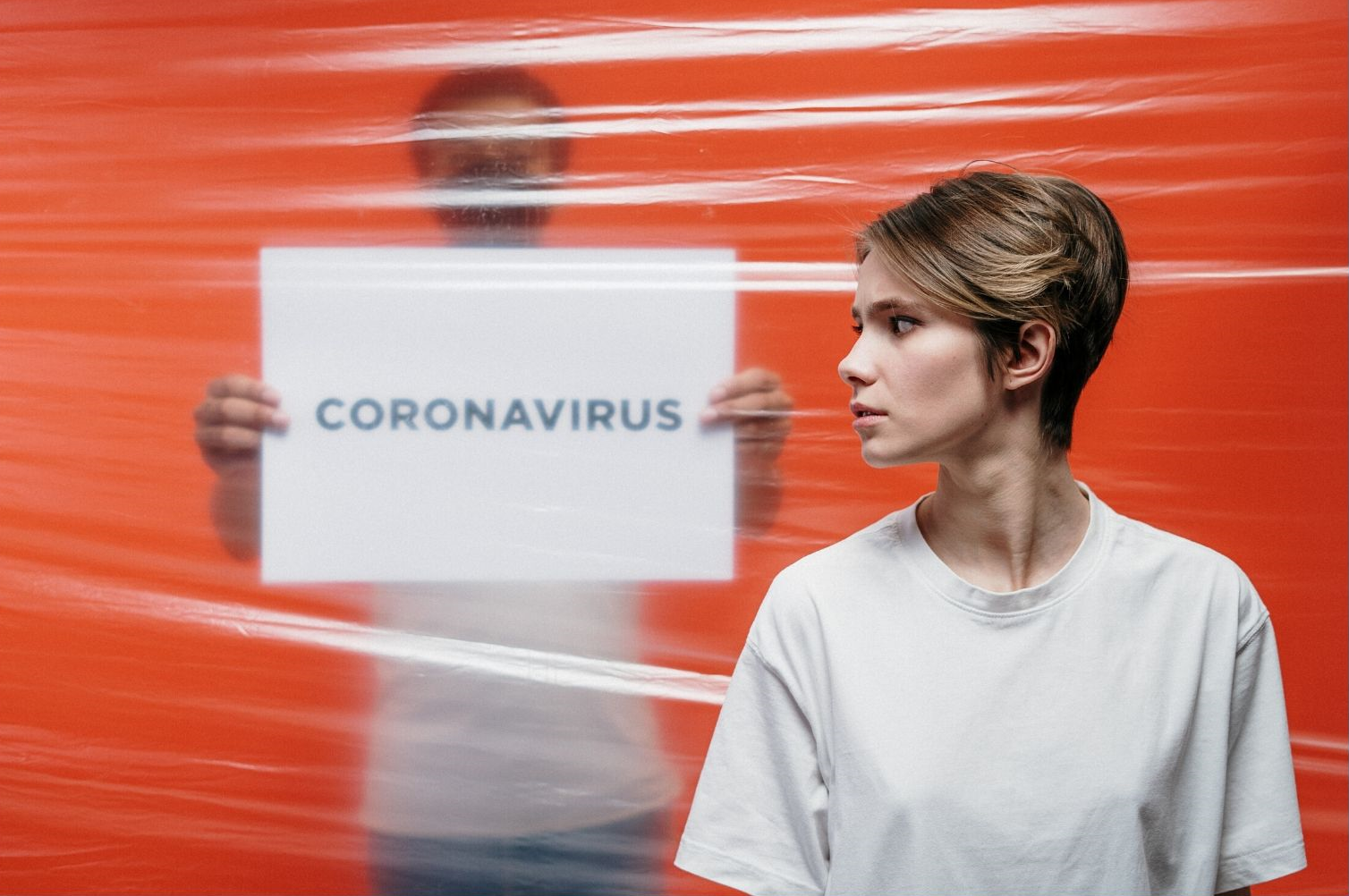 Lady worried looking back at coronavirus sign - whether her insurer will pay covid claims.